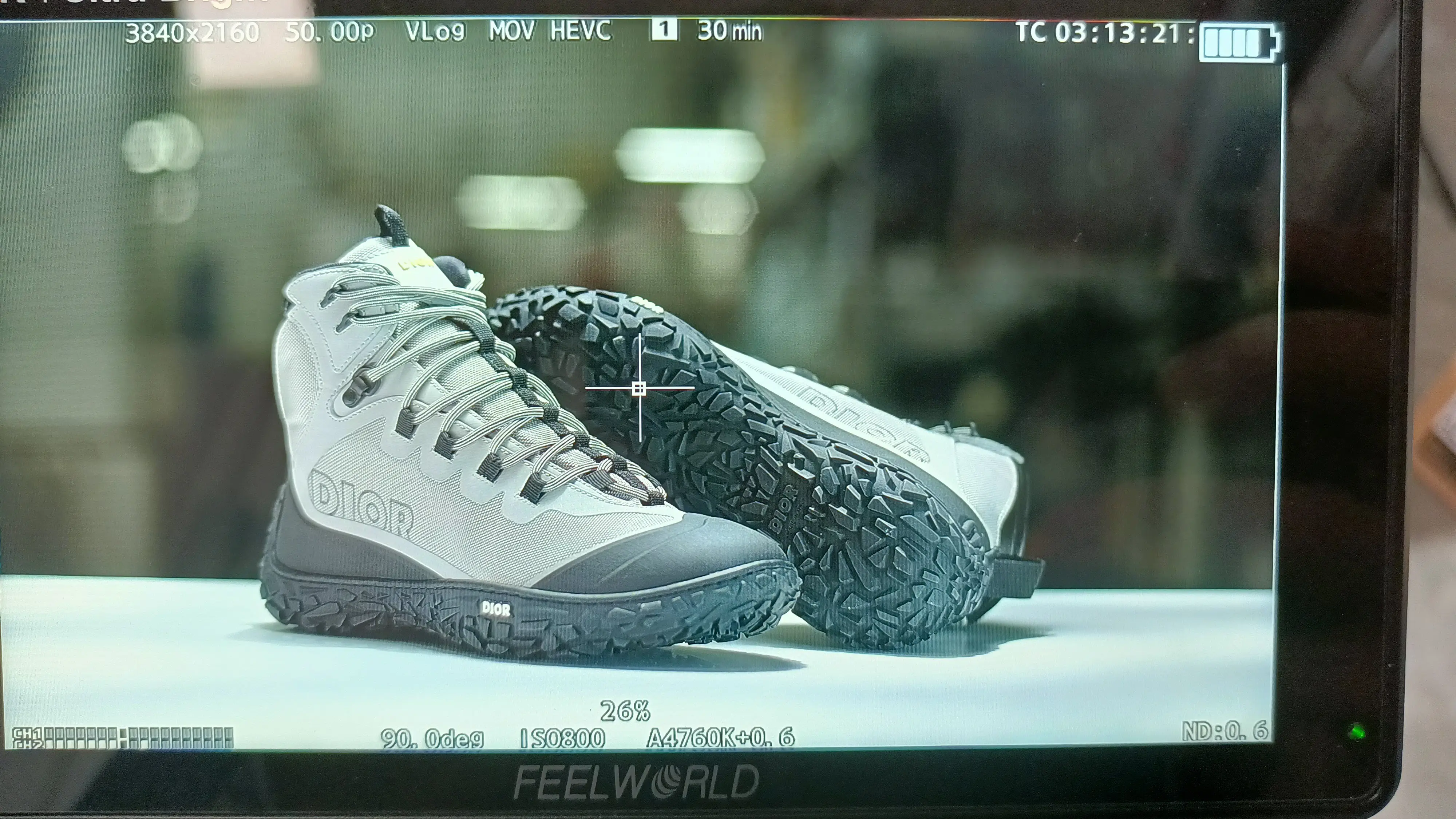 Feelworld field monitor showing a Dior sneaker framed on a white table inside a factory