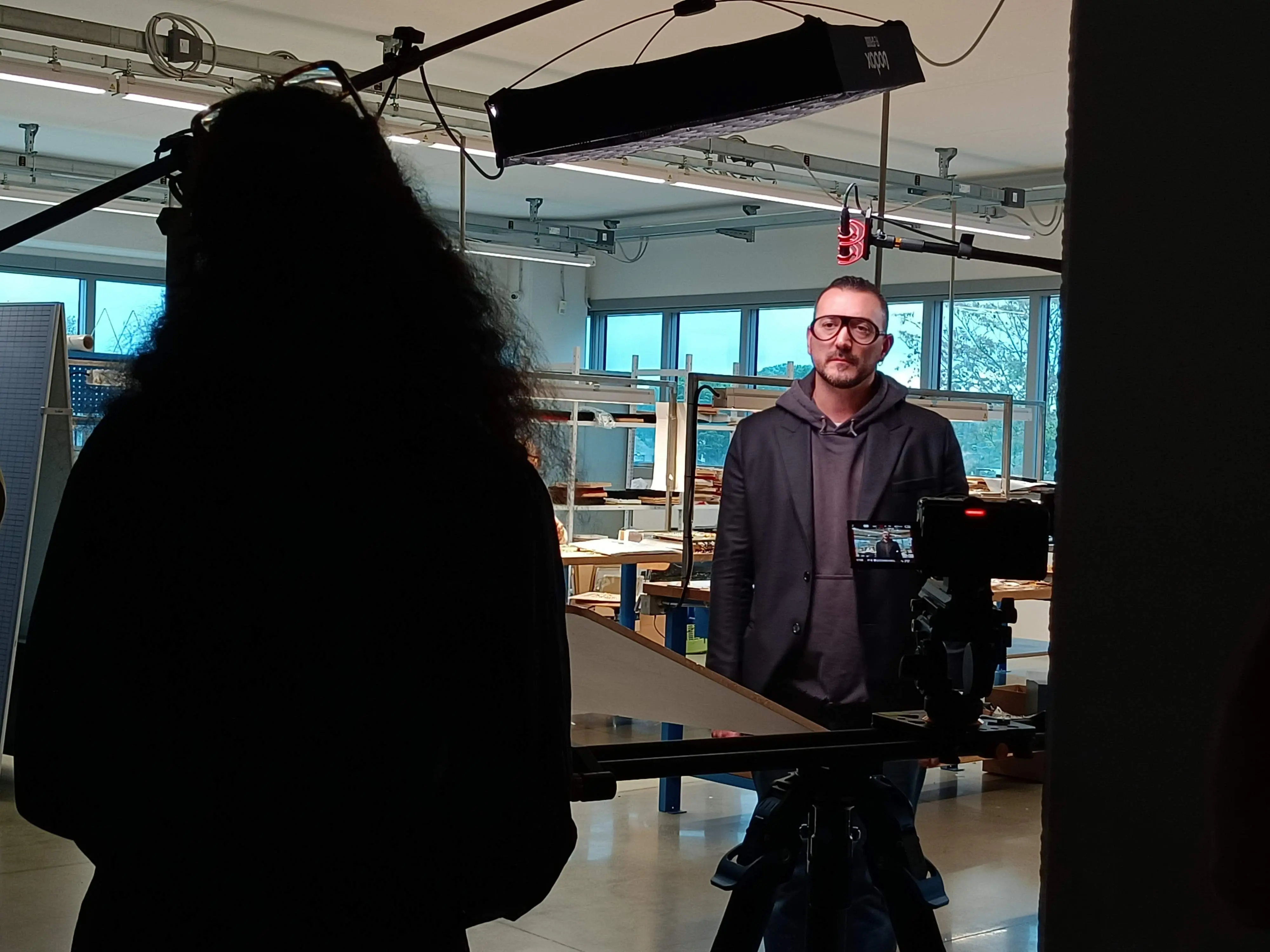 Matteo Castelli standing in a lit workshop during a Dior shoot, with the camera rigged in the foreground