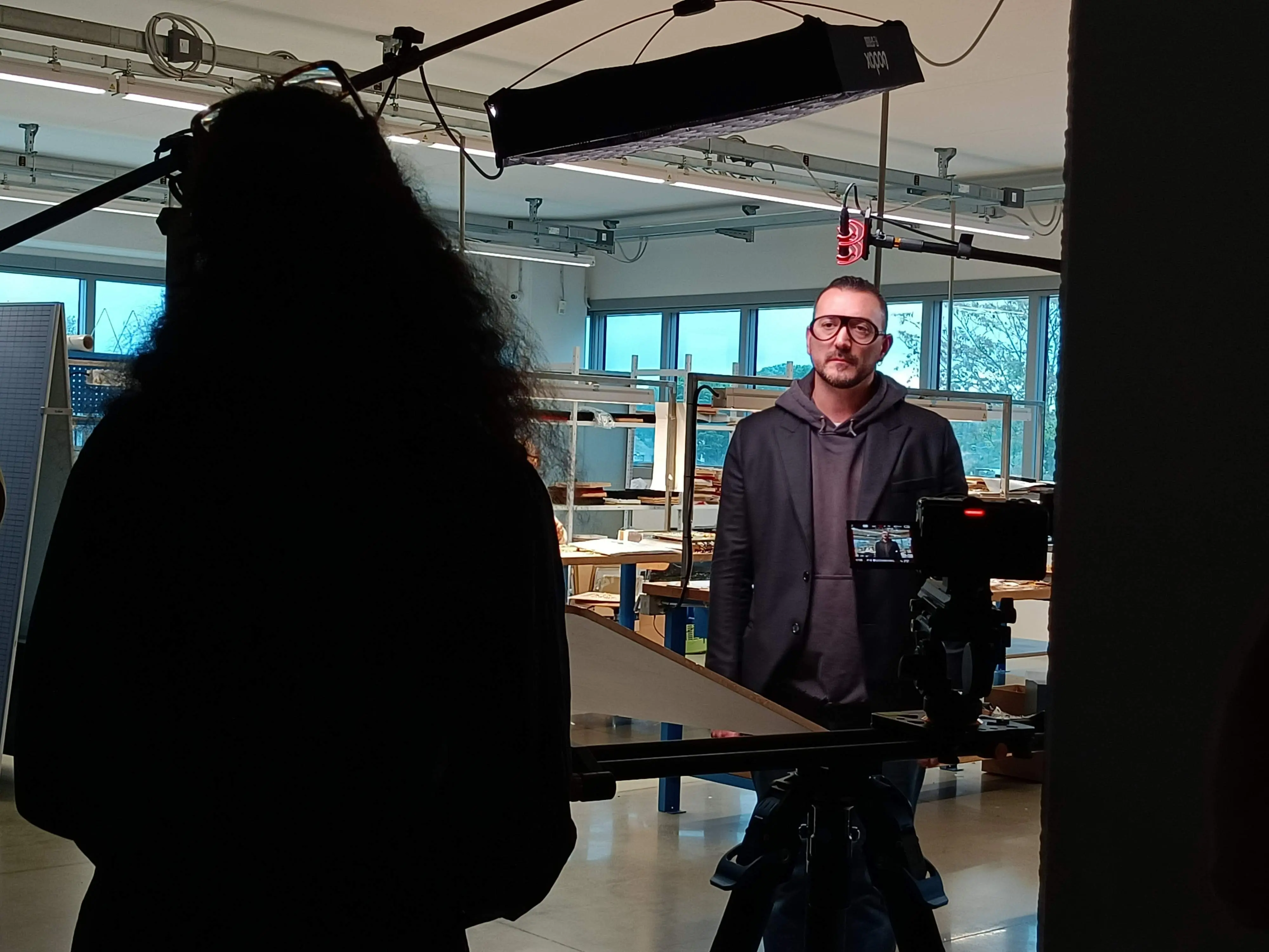 Matteo Castelli standing in a lit workshop during a Dior shoot, with the camera rigged in the foreground