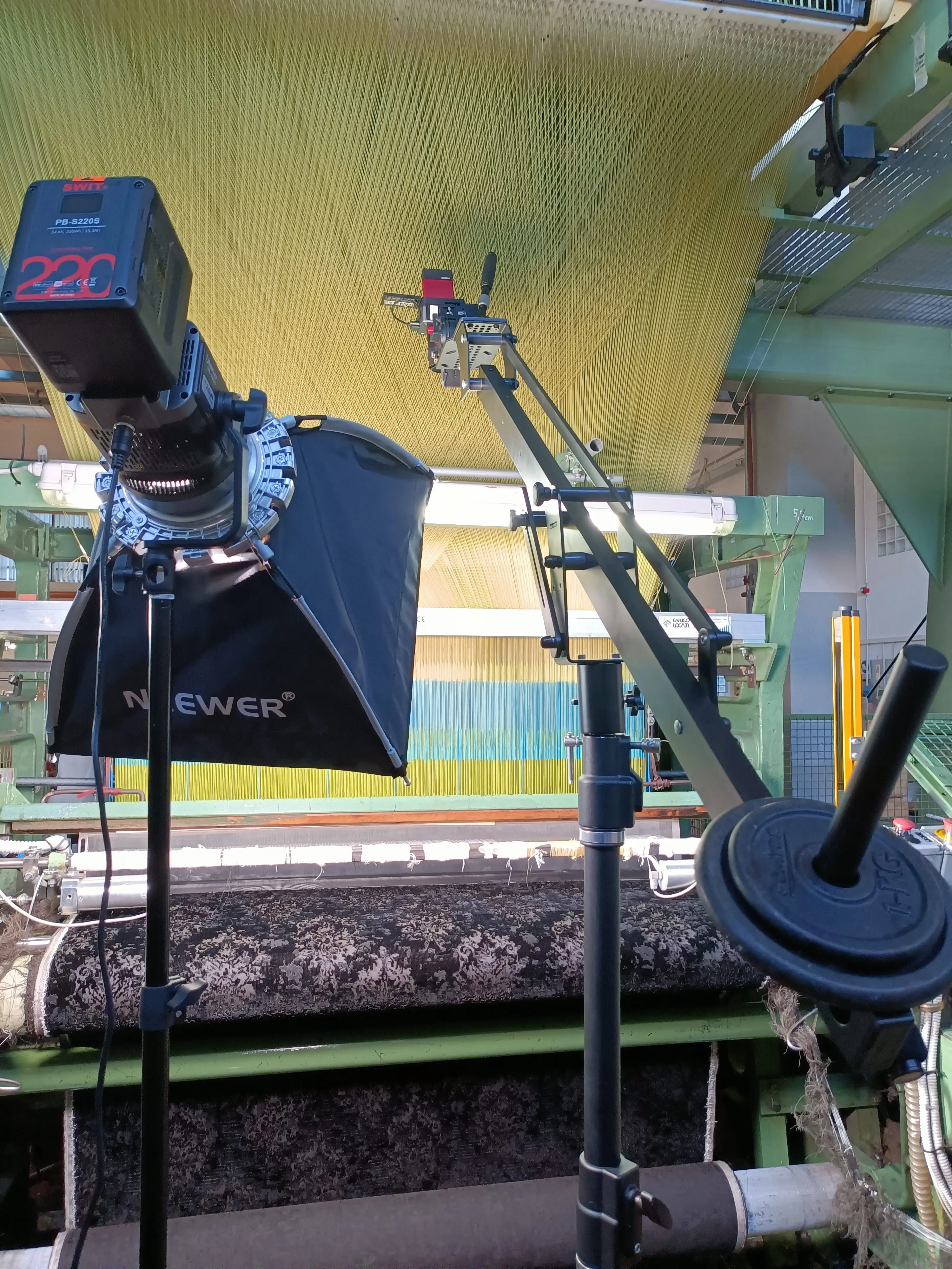 Small jib arm with a light rigged over a patterned textile on a loom during a Dior shoot