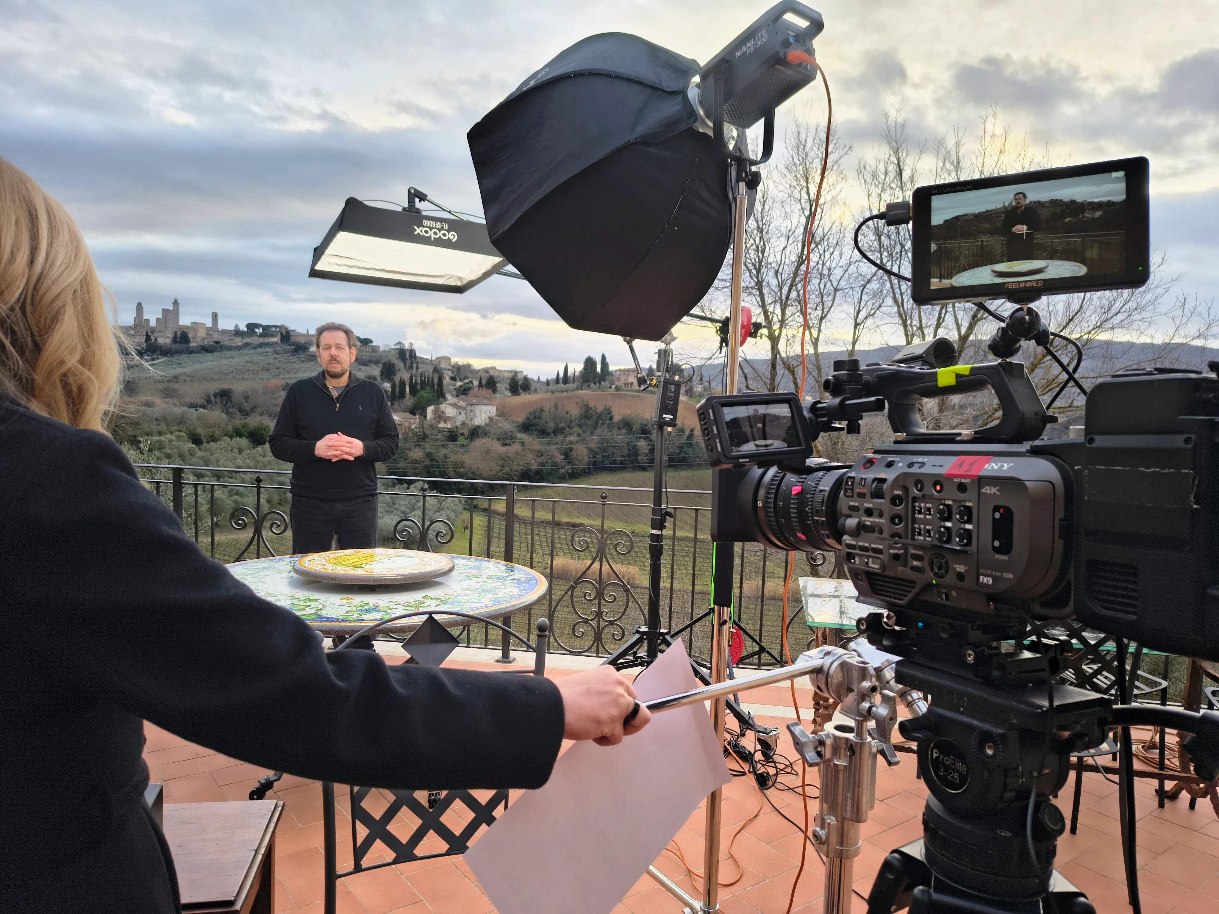 Interview shot on a terrace above the Tuscan hills with the towers of San Gimignano behind, Sony FX9 and softbox lighting