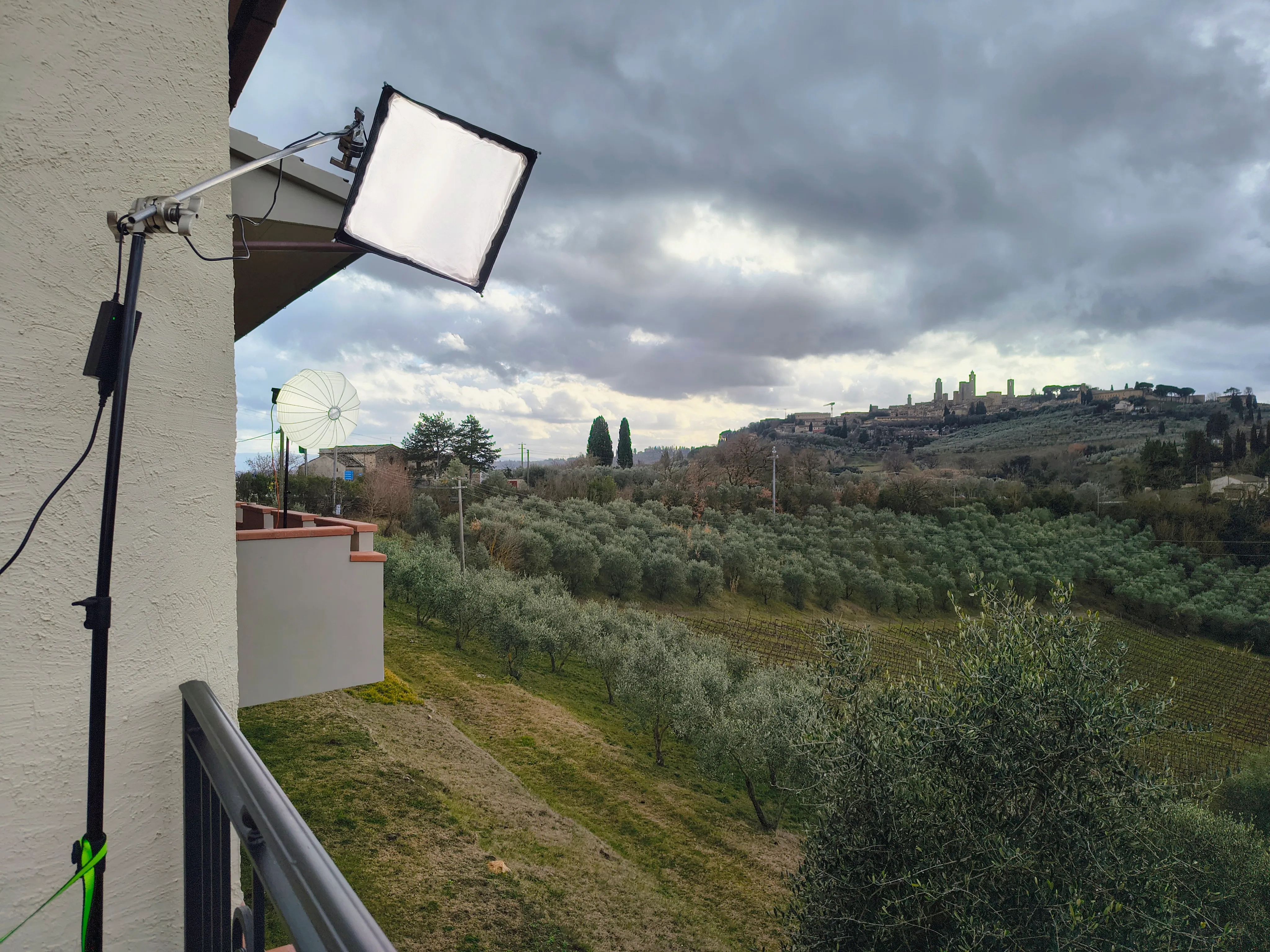 A softbox boomed out over the edge of the terrace and a china ball above the olive groves, with the towers of San Gimignano across the valley