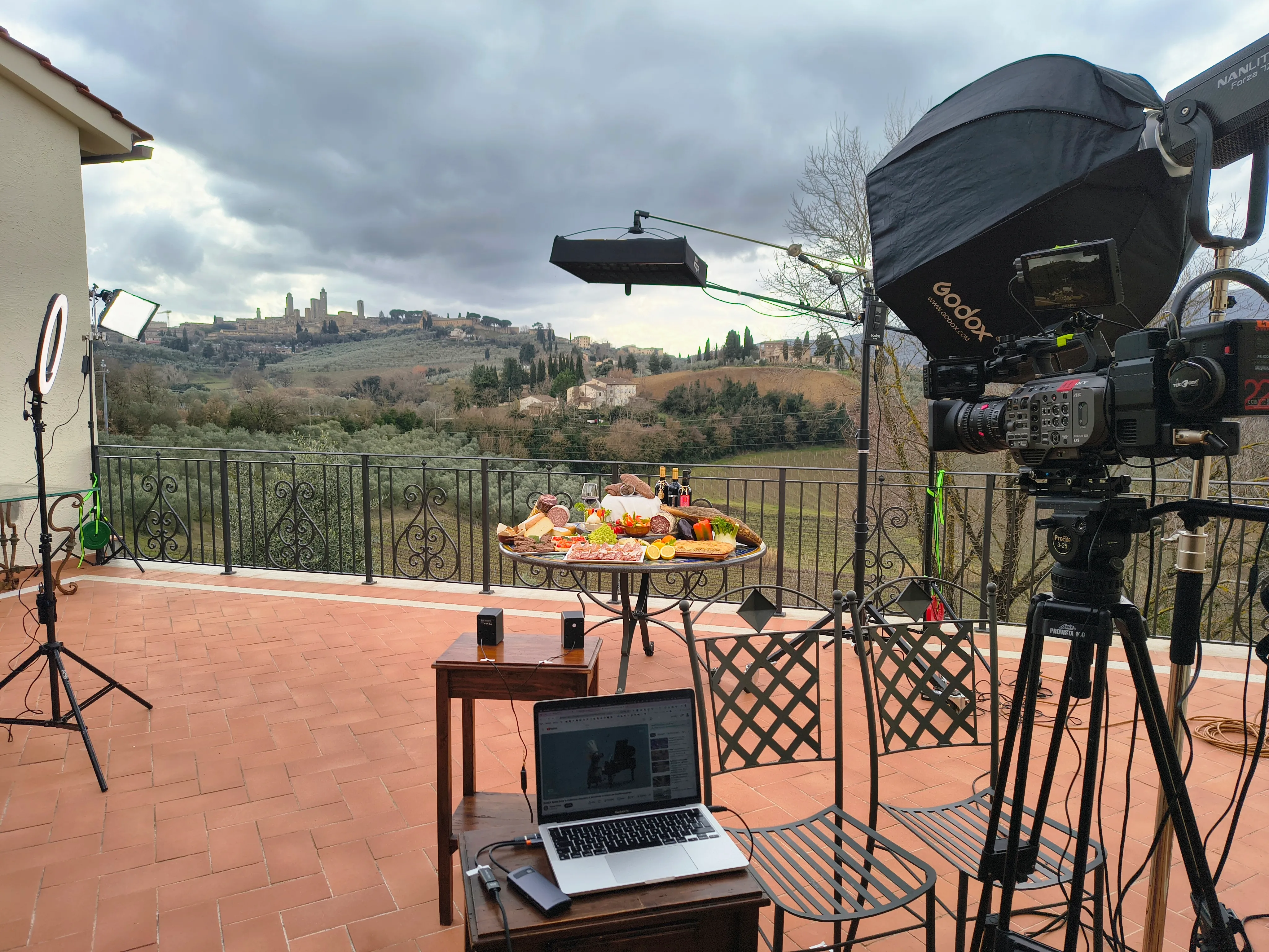 The full rig for the live stream on the winery terrace: a Sony FX9 on sticks, a Nanlite Forza 720 in a Godox softbox, a top light on a boom and the laptop carrying the video call