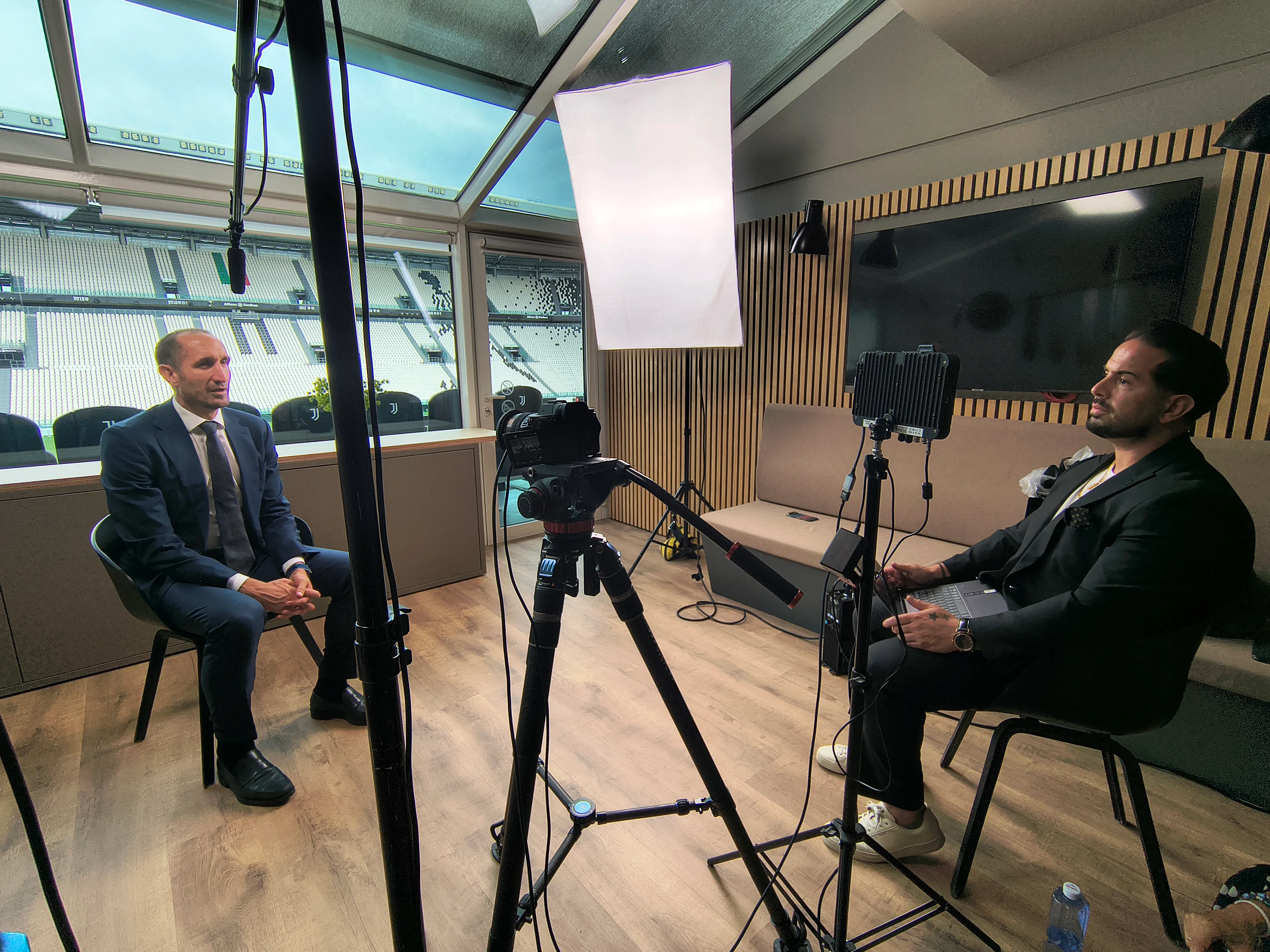 Interview filmed in a stadium hospitality room overlooking the pitch, with boom microphone, diffusion frame and LED panel