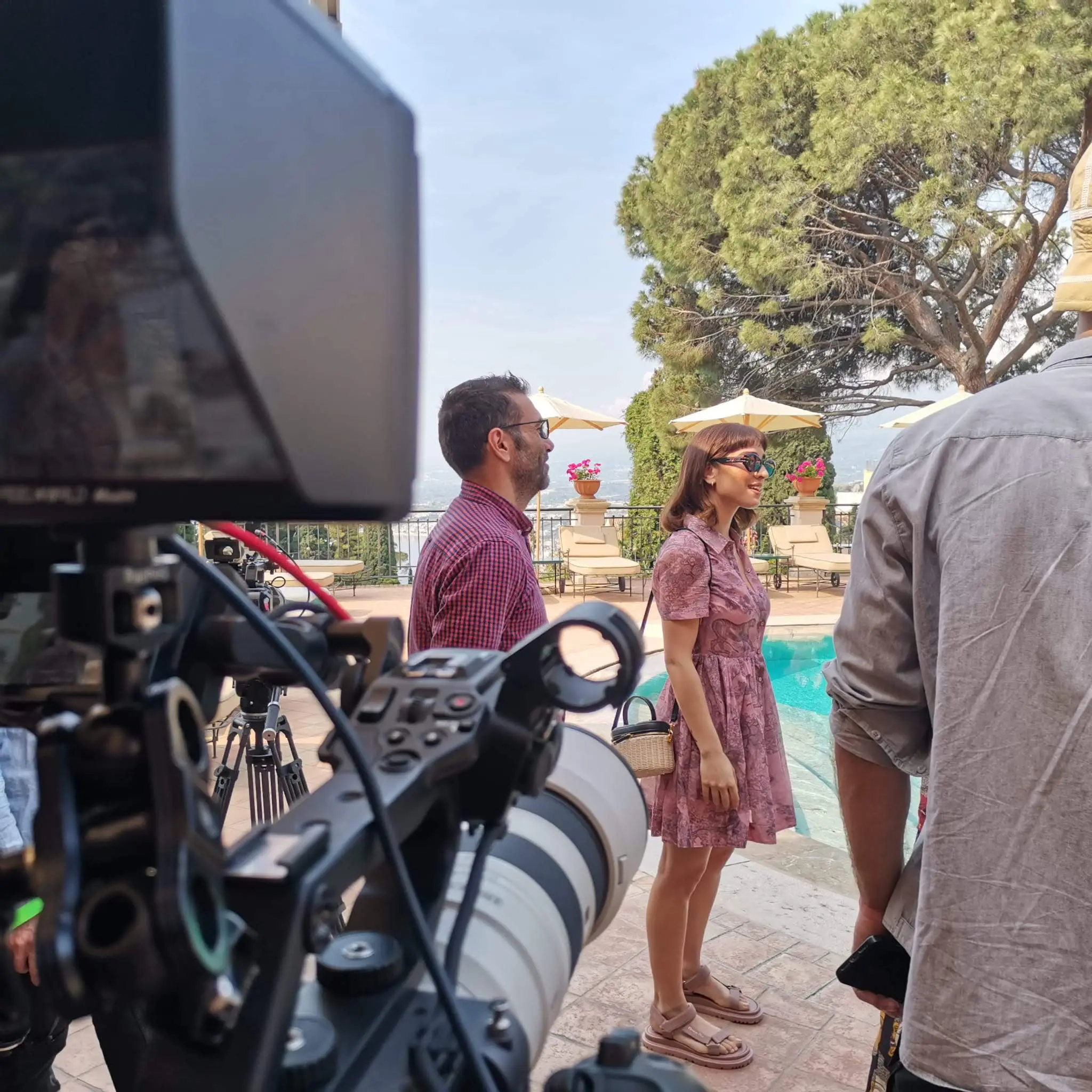 Cinema camera with a telephoto lens and field monitor in the foreground during a Dior shoot on a terrace in Taormina, Sicily